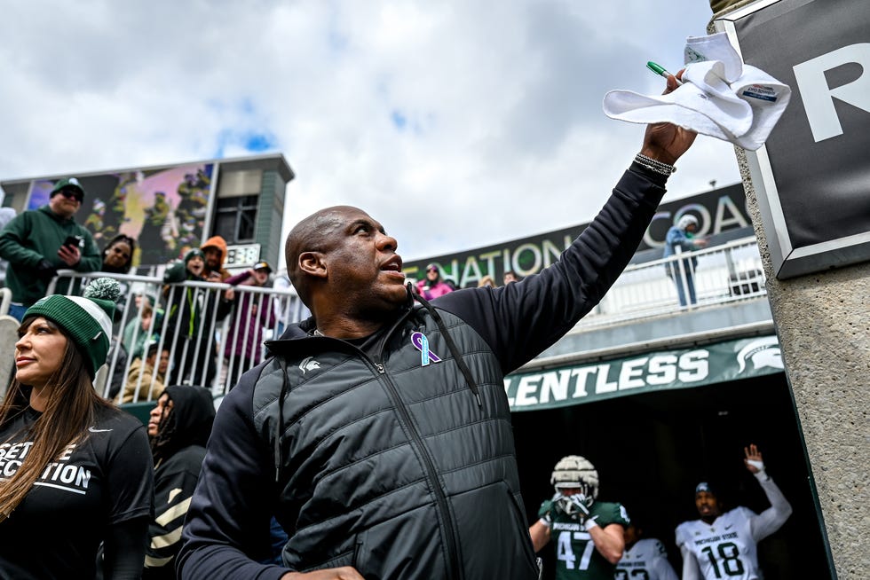 Michigan State's head coach, Mel Tucker, signs autographs for fans during a spring game on April 16, 2022, at Spartan Stadium in East Lansing, while rape survivor Brenda Tracy stands by his side.